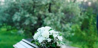 Coffin with white flowers outdoors in green surroundings