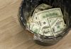 Trash bin filled with one hundred dollar bills