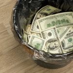Trash bin filled with one hundred dollar bills