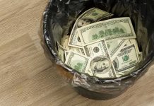Trash bin filled with one hundred dollar bills