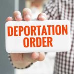 Hand holding sign with "Deportation Order" text.