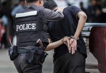 Police officer arrests handcuffed person