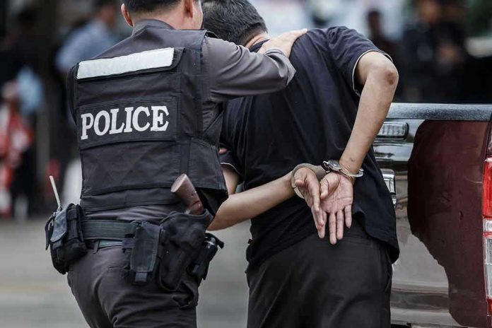 693957643 Police officer arrests handcuffed person