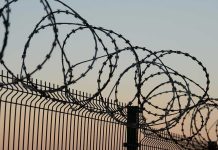 Barbed wire fence against sunset sky background