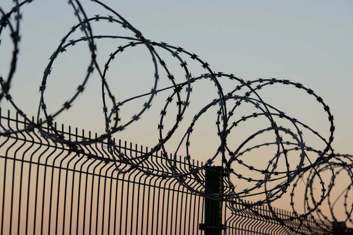 771028372 Barbed wire fence against sunset sky background