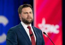 Man in a suit speaking at a podium.