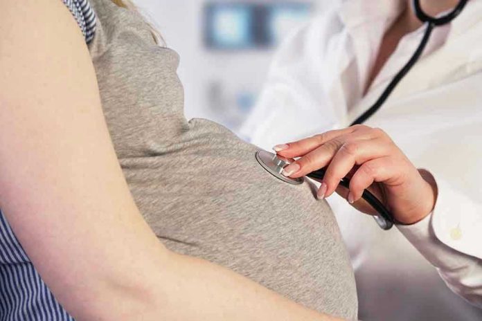 Doctor uses stethoscope on pregnant woman's belly.