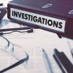 Documents and binder labeled "Investigations" on desk.