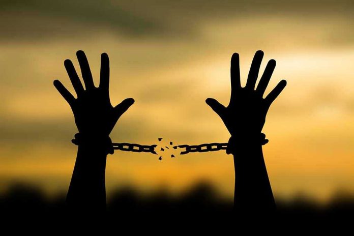 698153707 Hands breaking free from chains at sunset.