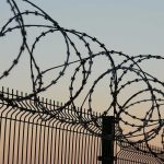 Barbed wire fence against sunset sky background