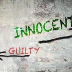 Graffiti on a wall depicting the words 'INNOCENT' and 'GUILTY' with arrows