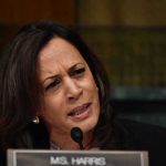 Woman speaking into a microphone while frowning.