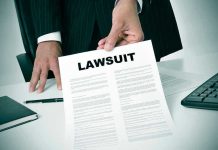 Person holding a document titled LAWSUIT in office.