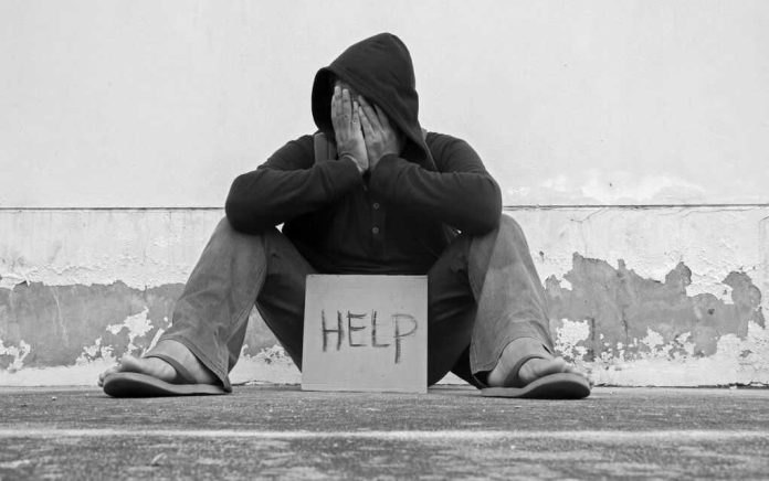 Person sitting holding sign that says help