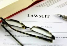 Lawsuit document with glasses, pen, and book.