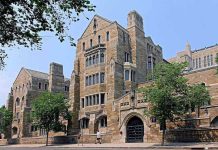 Historic university building with stone facade and surrounding trees