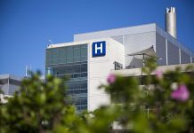 Modern hospital building with a prominent H sign against a clear blue sky