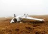 Overturned crashed airplane on grassy field.