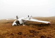 Overturned crashed airplane on grassy field.